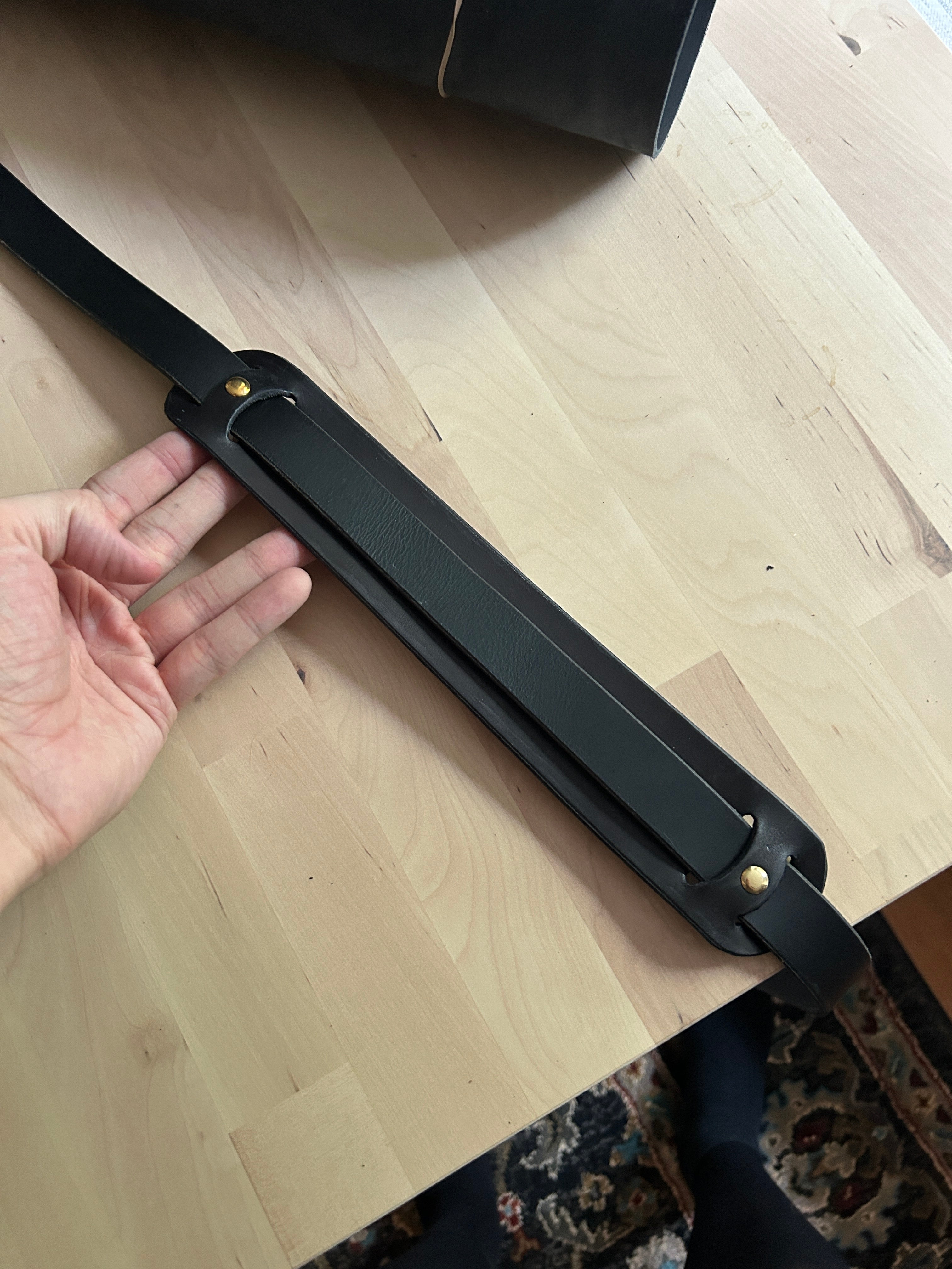 A black leather strap on a wooden table-top